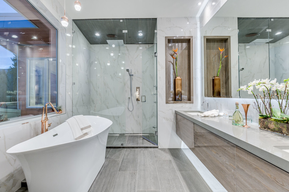Esempio di una stanza da bagno padronale moderna con vasca freestanding, doccia alcova, WC monopezzo, pareti bianche, lavabo sottopiano, pavimento grigio e porta doccia a battente