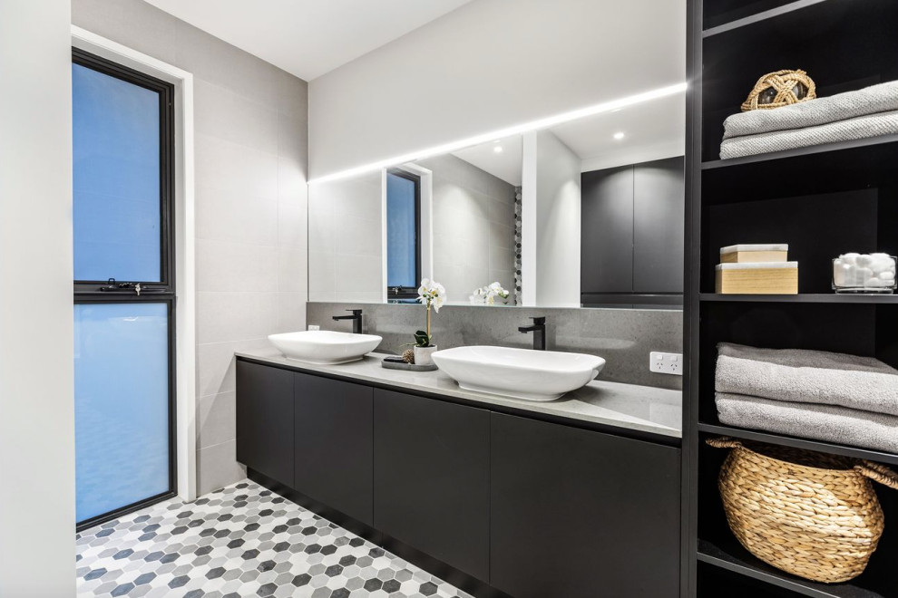 Стильный дизайн: главная ванная комната в современном стиле с плоскими фасадами, черными фасадами, серыми стенами, настольной раковиной, разноцветным полом, тумбой под две раковины и встроенной тумбой - последний тренд