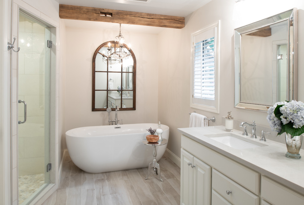Inspiration for a medium sized traditional ensuite wet room bathroom in Minneapolis with a freestanding bath, beige tiles, porcelain flooring, a submerged sink, engineered stone worktops, beige floors, a hinged door and white worktops.