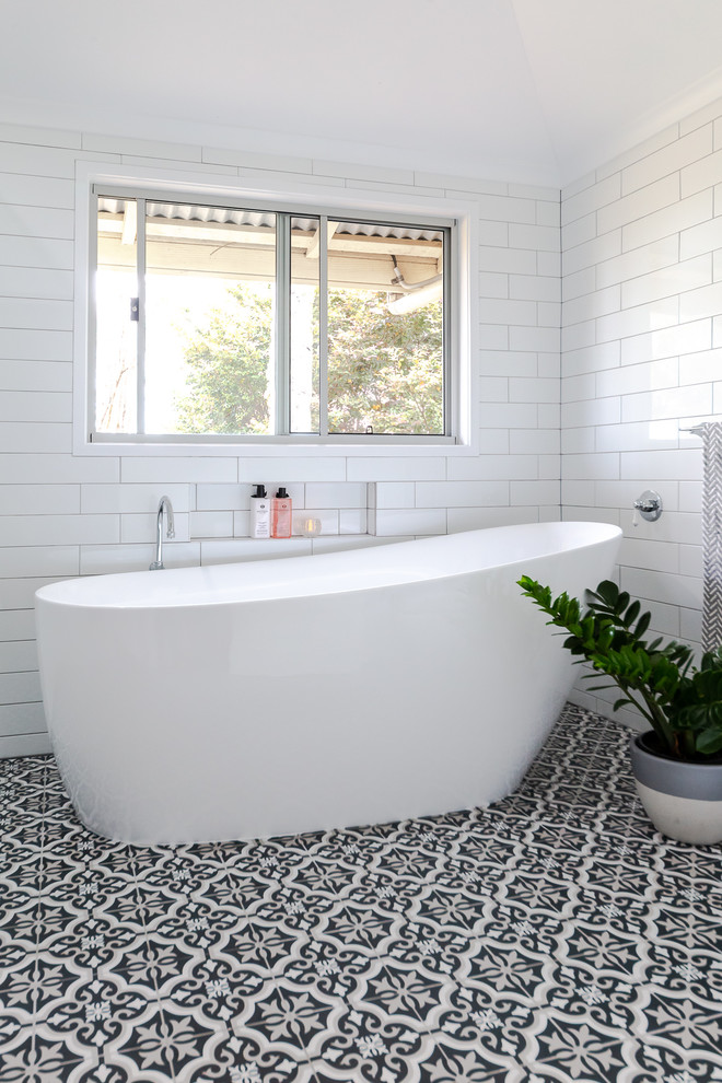 Klassisk inredning av ett mellanstort en-suite badrum, med ett fristående badkar, vit kakel, keramikplattor, vita väggar, klinkergolv i keramik och flerfärgat golv