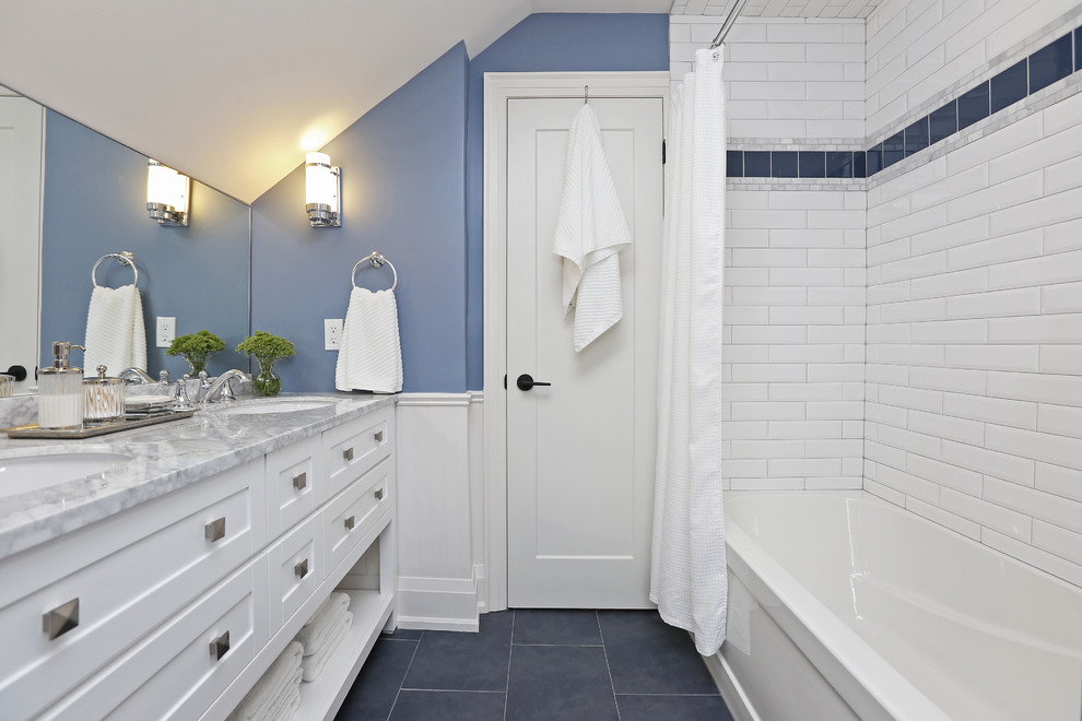Aménagement d'une salle de bain classique de taille moyenne pour enfant avec un placard à porte shaker, des portes de placard blanches, une baignoire en alcôve, un combiné douche/baignoire, un carrelage blanc, des carreaux de porcelaine, un mur bleu, un sol en carrelage de porcelaine, un lavabo encastré, un sol bleu, une cabine de douche avec un rideau, un plan de toilette gris et un plan de toilette en marbre.