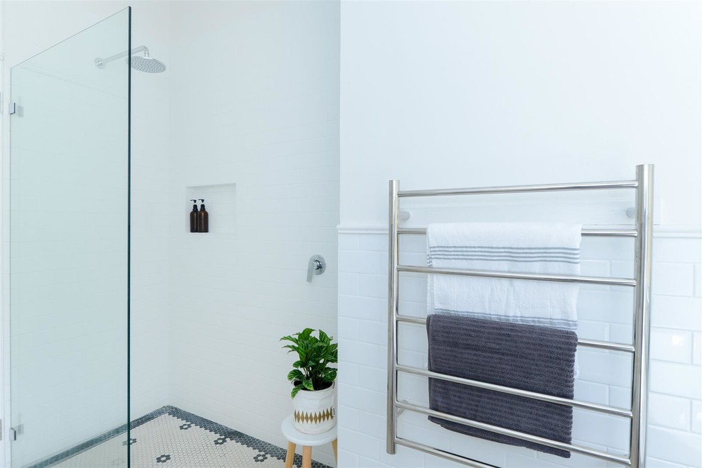 This is an example of a medium sized modern shower room bathroom with shaker cabinets, white cabinets, a freestanding bath, an alcove shower, a two-piece toilet, white tiles, ceramic tiles, white walls, mosaic tile flooring, a vessel sink, solid surface worktops, multi-coloured floors, an open shower and white worktops.