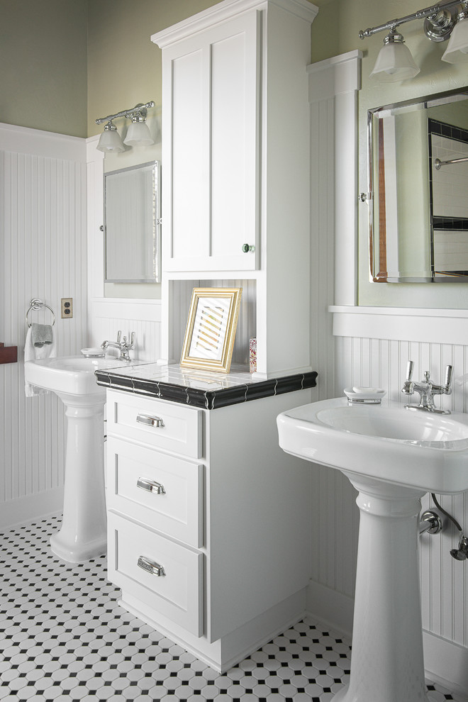 他の地域にあるトラディショナルスタイルのおしゃれな浴室 (シェーカースタイル扉のキャビネット、白いキャビネット、緑の壁、ペデスタルシンク、タイルの洗面台、マルチカラーの床、白い洗面カウンター) の写真