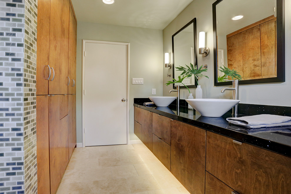 Medium sized modern bathroom in Houston with black and white tiles, a vessel sink, flat-panel cabinets, medium wood cabinets, quartz worktops, a built-in bath, a shower/bath combination, a one-piece toilet, ceramic tiles, grey walls and travertine flooring.