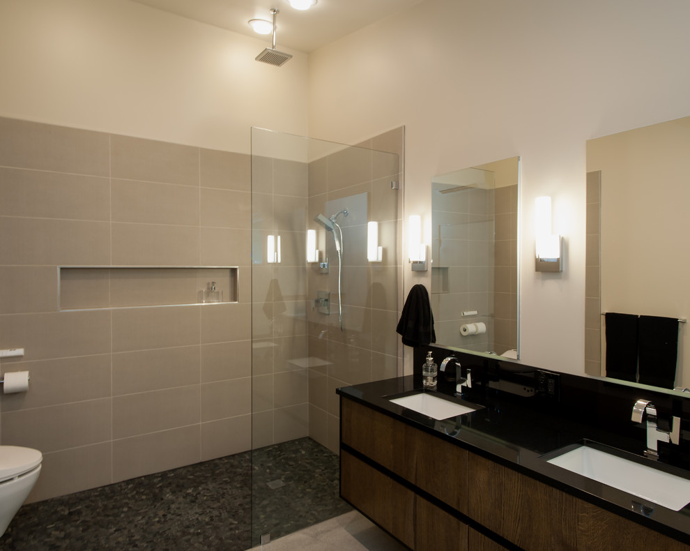 Idéer för att renovera ett mellanstort funkis en-suite badrum, med ett undermonterad handfat, släta luckor, skåp i mellenmörkt trä, bänkskiva i kvarts, ett fristående badkar, en kantlös dusch, en vägghängd toalettstol, grå kakel och betonggolv