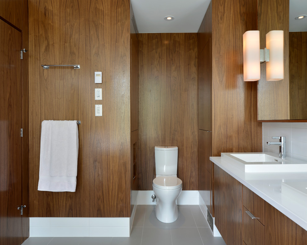 На фото: ванная комната в стиле модернизм с накладной раковиной, плоскими фасадами, фасадами цвета дерева среднего тона, раздельным унитазом и серой плиткой с