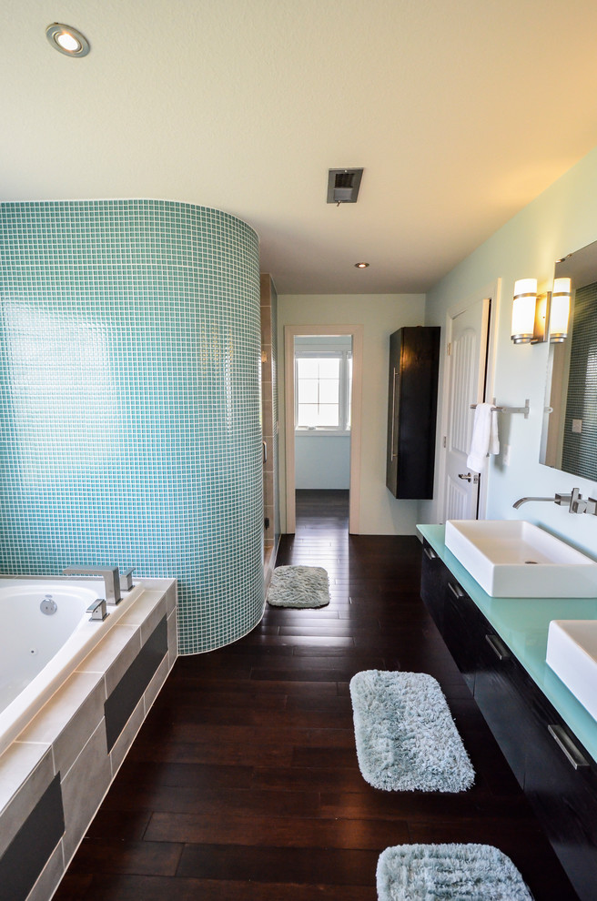 Modern inredning av ett stort en-suite badrum, med ett fristående handfat, släta luckor, skåp i mörkt trä, bänkskiva i glas, en öppen dusch, flerfärgad kakel, glaskakel, vita väggar, mörkt trägolv och ett badkar i en alkov
