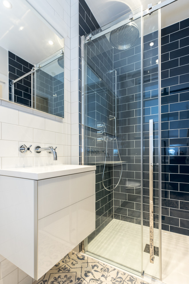 Medium sized modern shower room bathroom in London with flat-panel cabinets, white cabinets, a built-in shower, a one-piece toilet, blue tiles, ceramic tiles, white walls, ceramic flooring, a console sink, beige floors, a sliding door, white worktops, a wall niche, a single sink and a floating vanity unit.