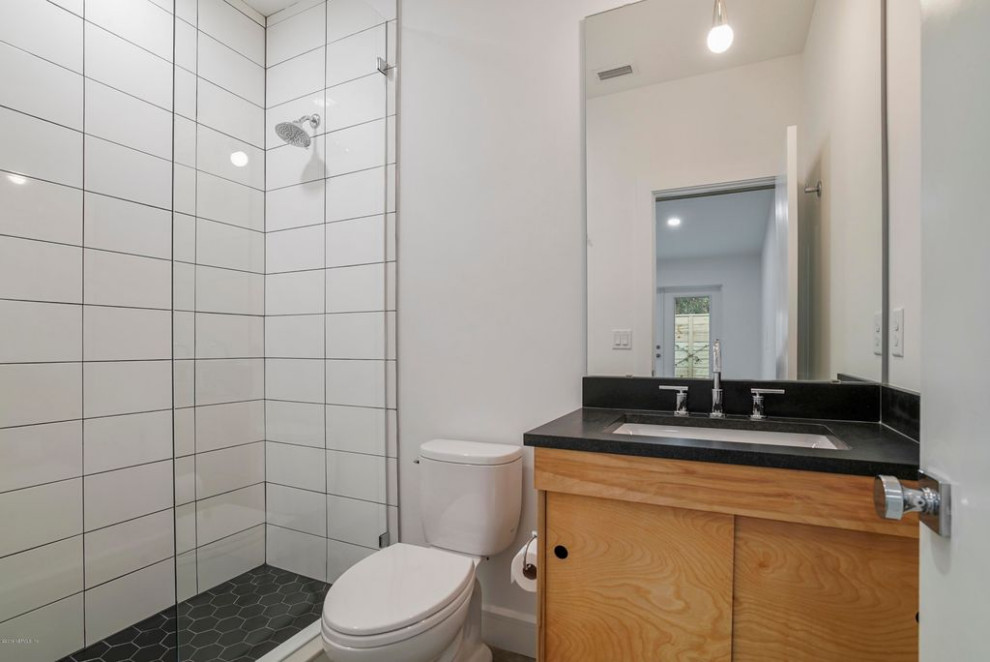 Cette photo montre une salle de bain principale moderne de taille moyenne avec un placard à porte plane, des portes de placard marrons, une douche ouverte, WC à poser, un carrelage blanc, des carreaux de céramique, un mur blanc, sol en béton ciré, un lavabo intégré, un plan de toilette en quartz, un sol gris, aucune cabine, un plan de toilette noir, un banc de douche, meuble simple vasque, meuble-lavabo suspendu et un plafond voûté.