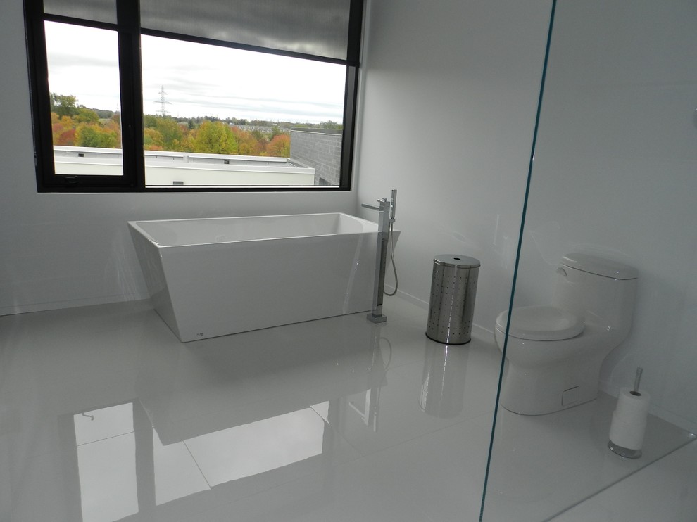 Large modern ensuite bathroom in Toronto with white cabinets, a freestanding bath, a one-piece toilet, white tiles, porcelain tiles, white walls and porcelain flooring.