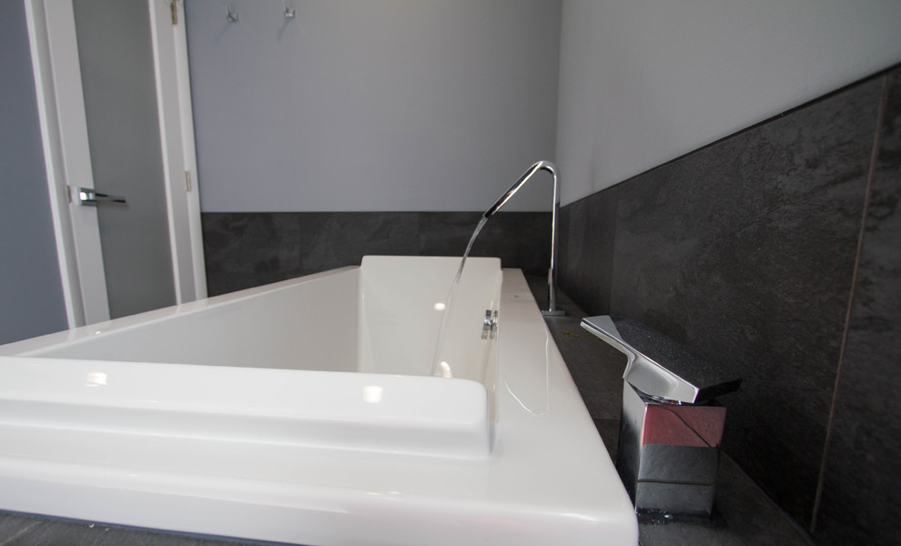 Ejemplo de cuarto de baño principal moderno de tamaño medio con bañera encastrada, baldosas y/o azulejos negros, baldosas y/o azulejos de porcelana, paredes grises, suelo de baldosas de porcelana y suelo blanco