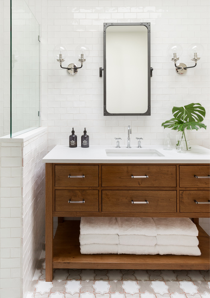 Cette photo montre une salle de bain moderne en bois brun avec un placard avec porte à panneau encastré, une douche d'angle, un carrelage blanc, des carreaux de céramique, un mur blanc, tomettes au sol, un lavabo encastré, un plan de toilette en quartz et un sol blanc.