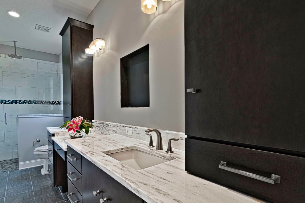 Contemporary ensuite bathroom in Jacksonville with flat-panel cabinets, dark wood cabinets, a one-piece toilet, grey tiles, ceramic tiles, grey walls, porcelain flooring, a submerged sink, engineered stone worktops, black floors and white worktops.