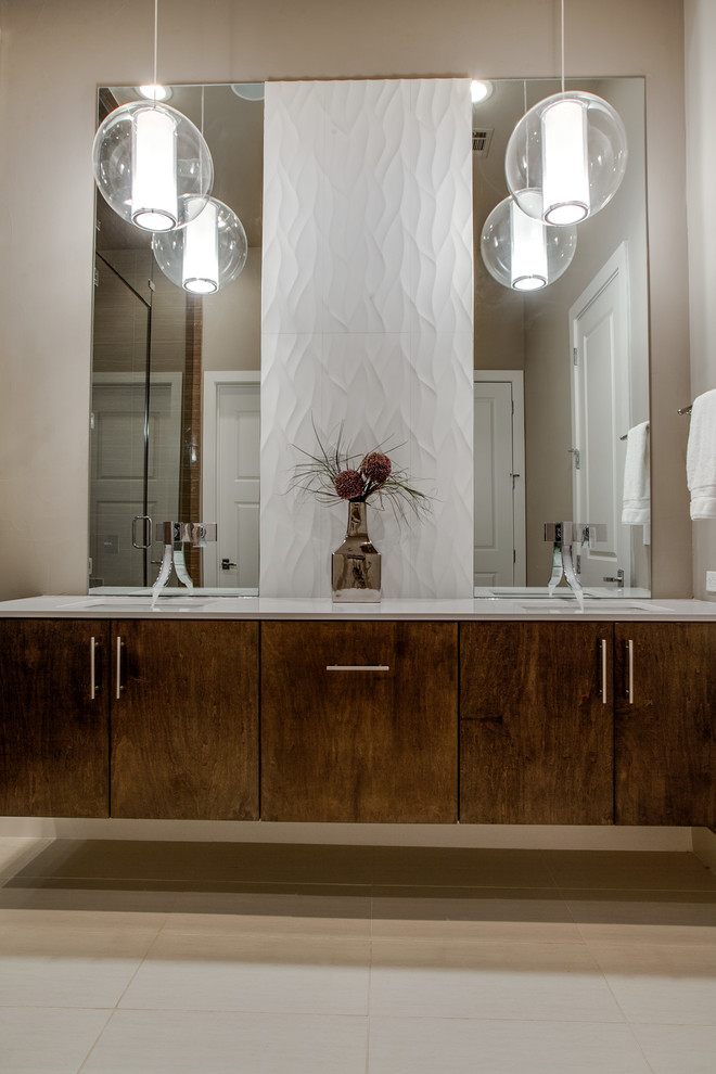 Inredning av ett modernt badrum, med ett integrerad handfat, släta luckor, skåp i mellenmörkt trä, ett badkar i en alkov, en dusch/badkar-kombination och vit kakel