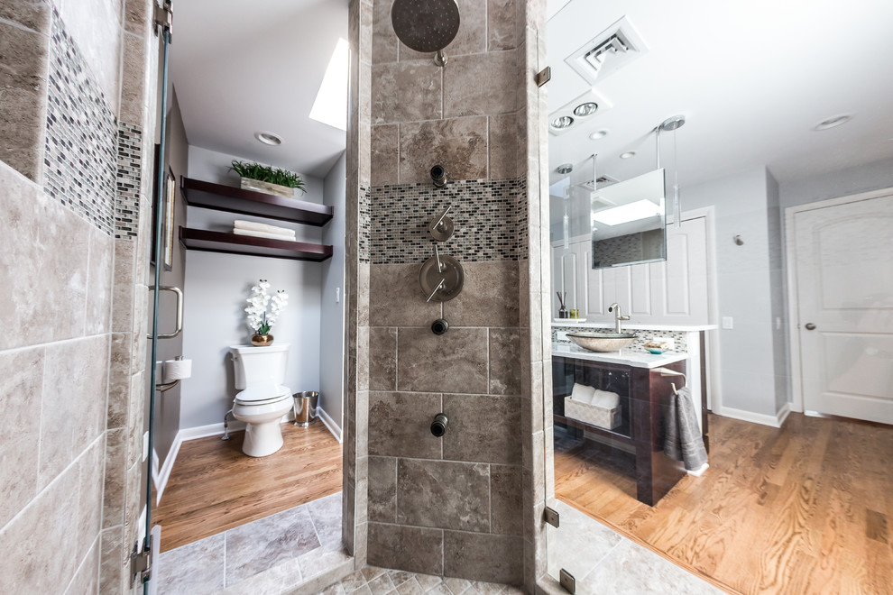 Example of a mid-sized trendy master gray tile and porcelain tile medium tone wood floor and multicolored floor doorless shower design in Other with a vessel sink, flat-panel cabinets, dark wood cabinets, quartz countertops, a one-piece toilet, gray walls and a hinged shower door