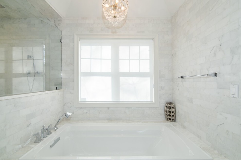 Cette image montre une salle de bain principale minimaliste avec un carrelage blanc, un mur gris, un sol en marbre, un plan de toilette en marbre, une baignoire posée et un carrelage métro.