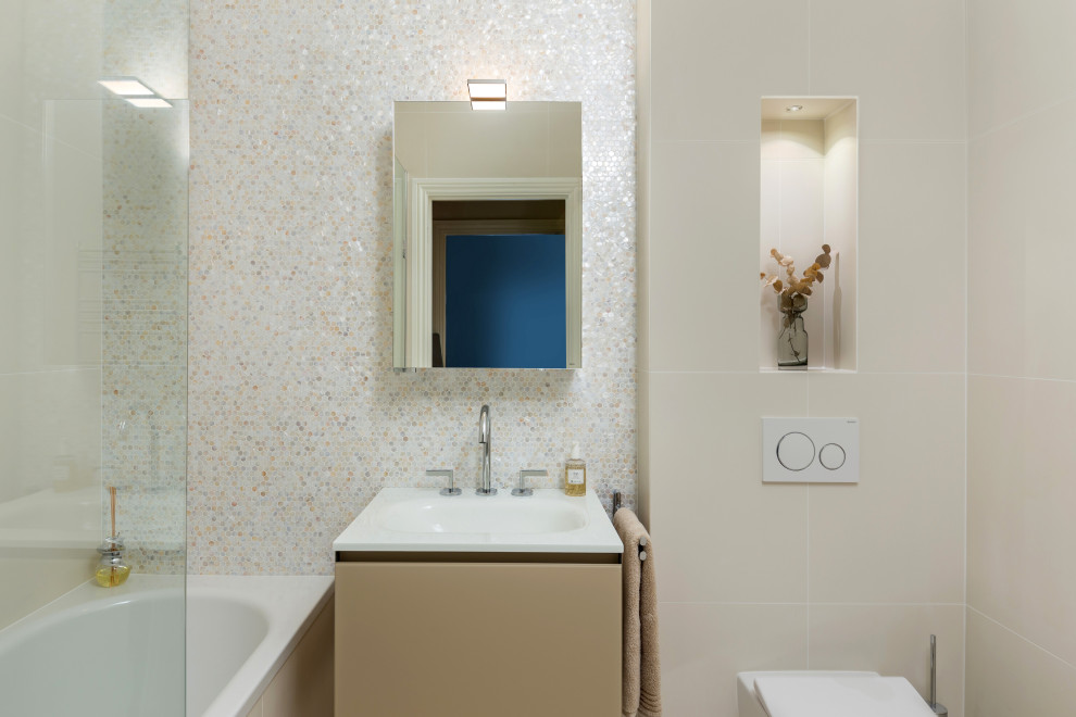 Modern inredning av ett litet vit vitt badrum, med luckor med glaspanel, beige skåp, ett platsbyggt badkar, en dusch/badkar-kombination, en vägghängd toalettstol, beige kakel, mosaik, beige väggar, klinkergolv i porslin, ett integrerad handfat, bänkskiva i glas, beiget golv och dusch med gångjärnsdörr