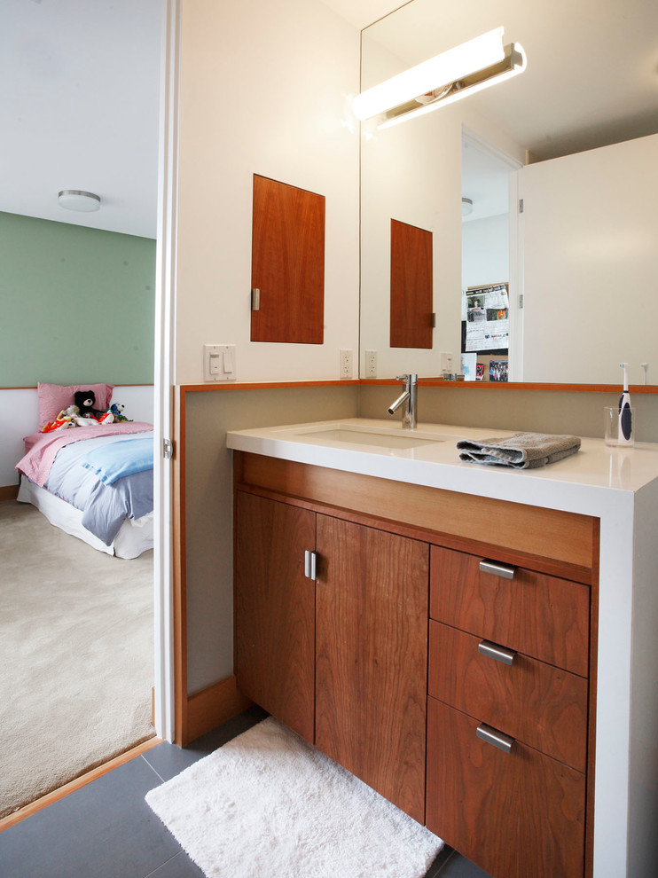 Cette image montre une salle de bain design en bois brun pour enfant avec un lavabo encastré et un placard à porte plane.