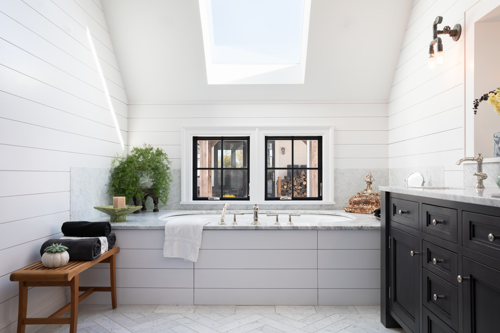 Example of a mid-sized farmhouse master white floor bathroom design in New York with recessed-panel cabinets, black cabinets, an undermount tub, white walls and gray countertops