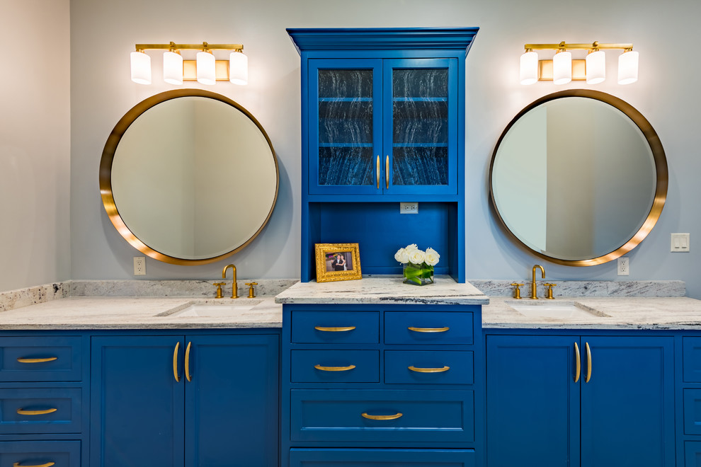 Diseño de cuarto de baño principal tradicional renovado de tamaño medio con armarios con paneles lisos, puertas de armario azules, bañera encastrada, paredes amarillas, suelo de baldosas de porcelana, lavabo bajoencimera, encimera de granito y suelo gris