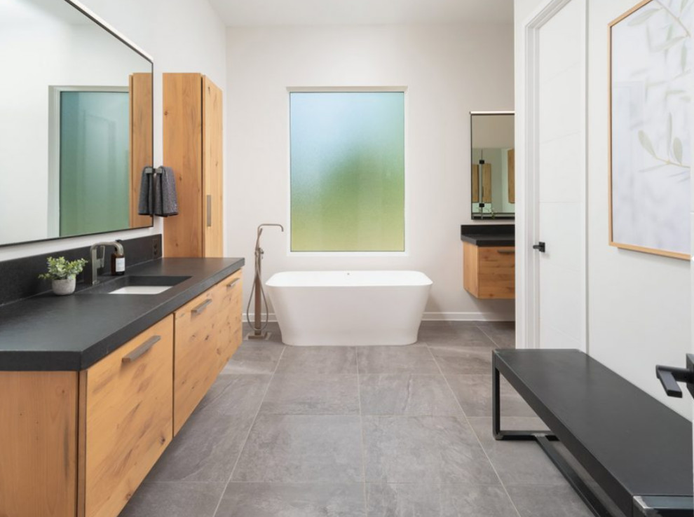 Пример оригинального дизайна: большая главная ванная комната в стиле модернизм с плоскими фасадами, светлыми деревянными фасадами, отдельно стоящей ванной, душем в нише, белыми стенами, полом из сланца, врезной раковиной, столешницей из кварцита, серым полом и черной столешницей