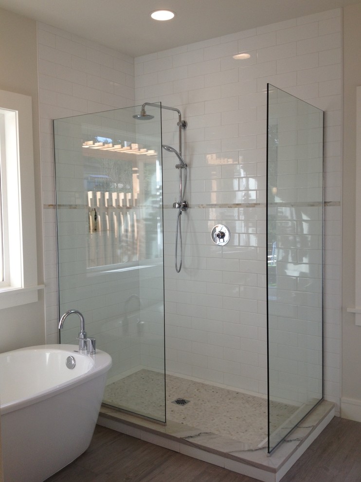 Cette photo montre une salle de bain principale moderne avec une baignoire indépendante, une douche ouverte, des carreaux de céramique, un mur blanc, un carrelage blanc et un sol en carrelage de céramique.