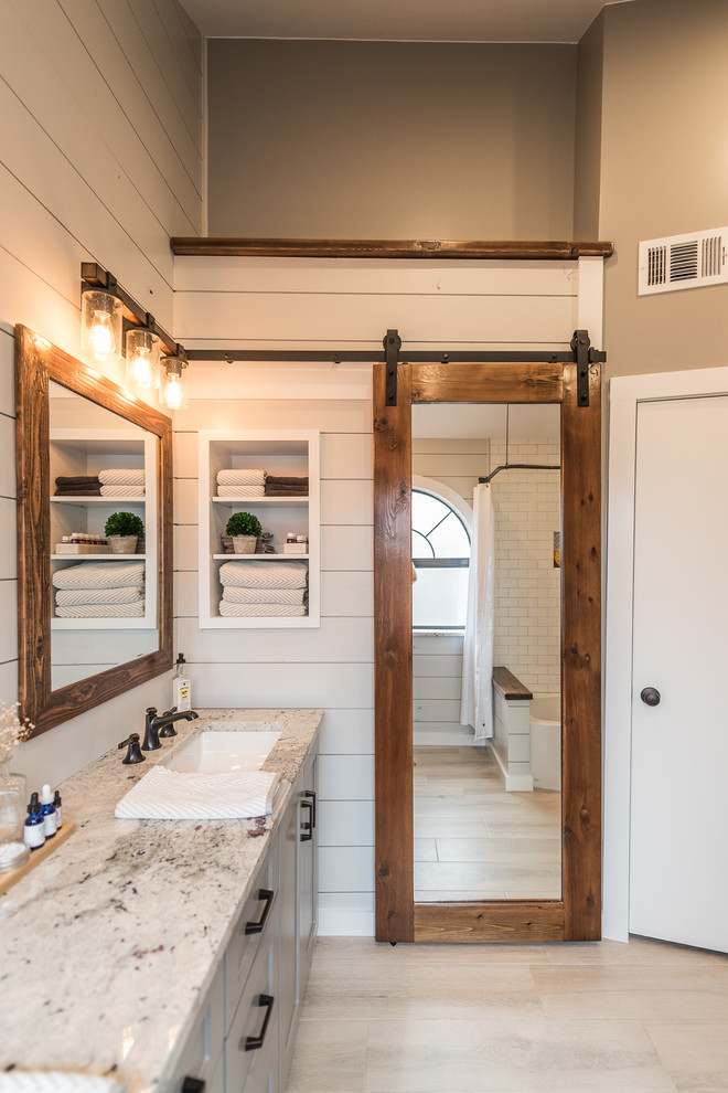 Bathroom - mid-sized cottage master gray tile and porcelain tile porcelain tile bathroom idea in Dallas with shaker cabinets, gray cabinets, a one-piece toilet, gray walls, an undermount sink and granite countertops