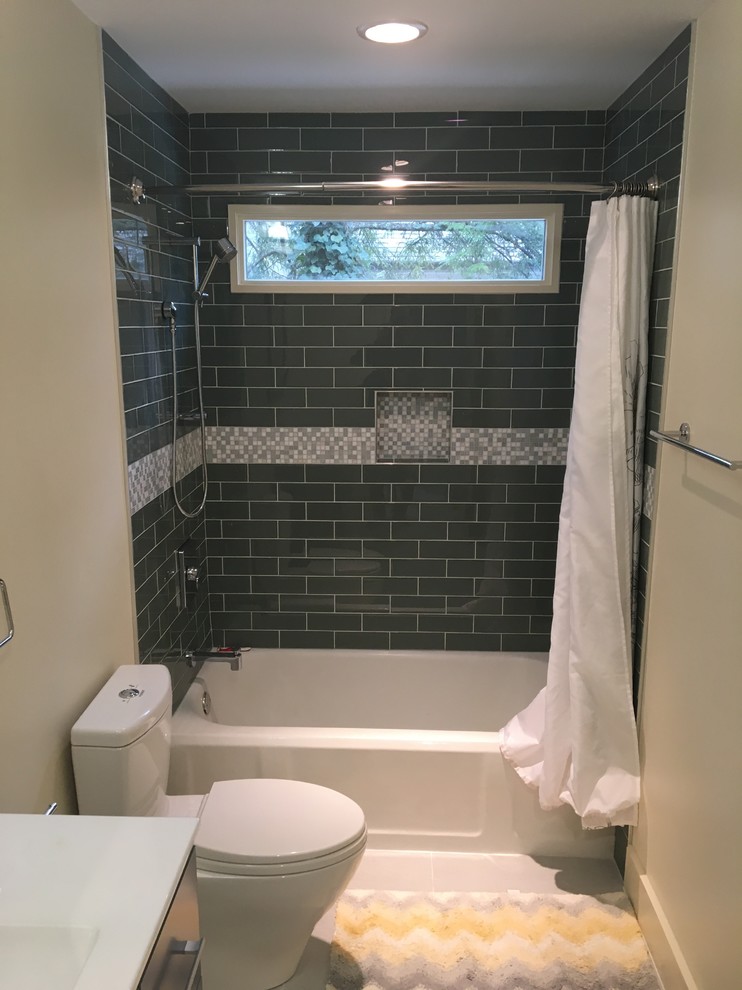 Inredning av ett lantligt mellanstort badrum, med möbel-liknande, grå skåp, ett badkar i en alkov, en dusch/badkar-kombination, en toalettstol med hel cisternkåpa, blå kakel, tunnelbanekakel, beige väggar, ett integrerad handfat, bänkskiva i kvarts, grått golv och dusch med duschdraperi