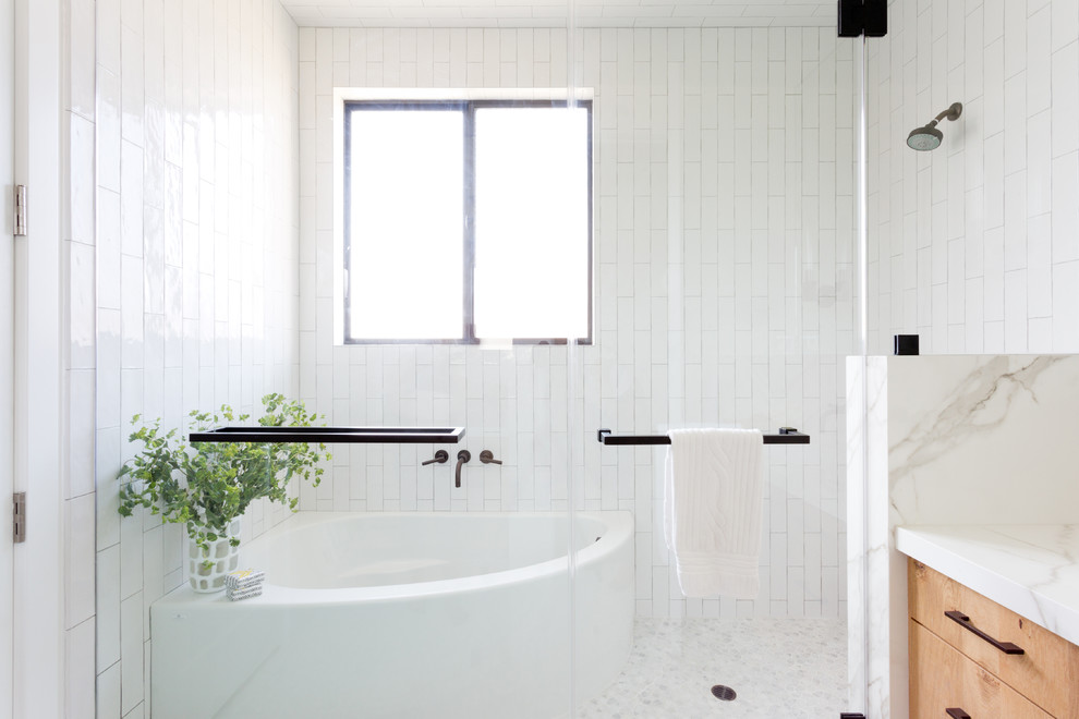 Réalisation d'une salle de bain principale nordique en bois clair avec un placard à porte plane, une douche d'angle, un mur blanc, un sol en galet, un lavabo encastré, un plan de toilette en marbre, un sol blanc et une cabine de douche à porte battante.