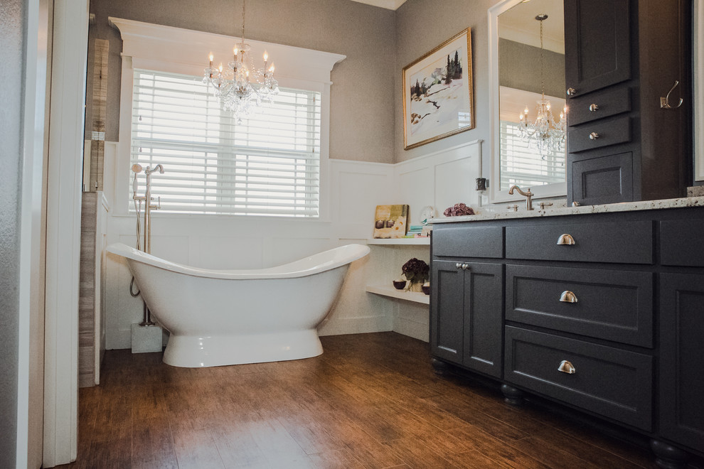 Freestanding bathtub - mid-sized traditional master dark wood floor and brown floor freestanding bathtub idea in Dallas with recessed-panel cabinets, black cabinets, gray walls and granite countertops