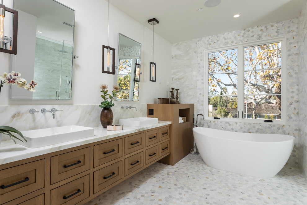 Пример оригинального дизайна: главная ванная комната в стиле кантри с фасадами в стиле шейкер, фасадами цвета дерева среднего тона, отдельно стоящей ванной, белыми стенами, настольной раковиной, разноцветным полом и серой столешницей