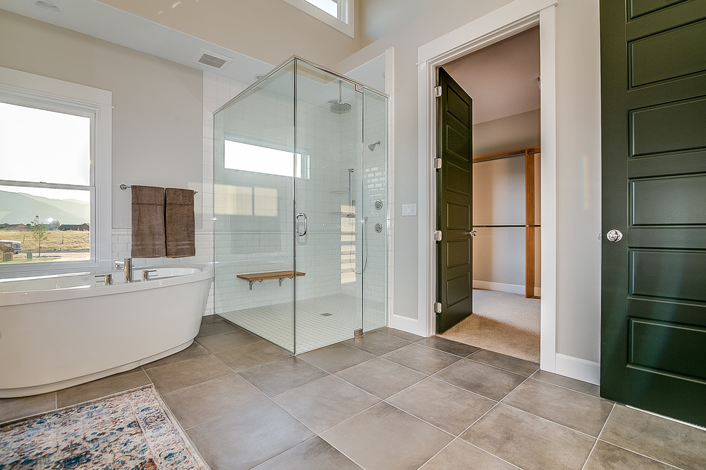 Cette photo montre une grande salle de bain principale nature avec une baignoire indépendante, une douche d'angle, un carrelage blanc, un carrelage métro, un mur gris, un sol en carrelage de céramique, un sol marron et une cabine de douche à porte battante.