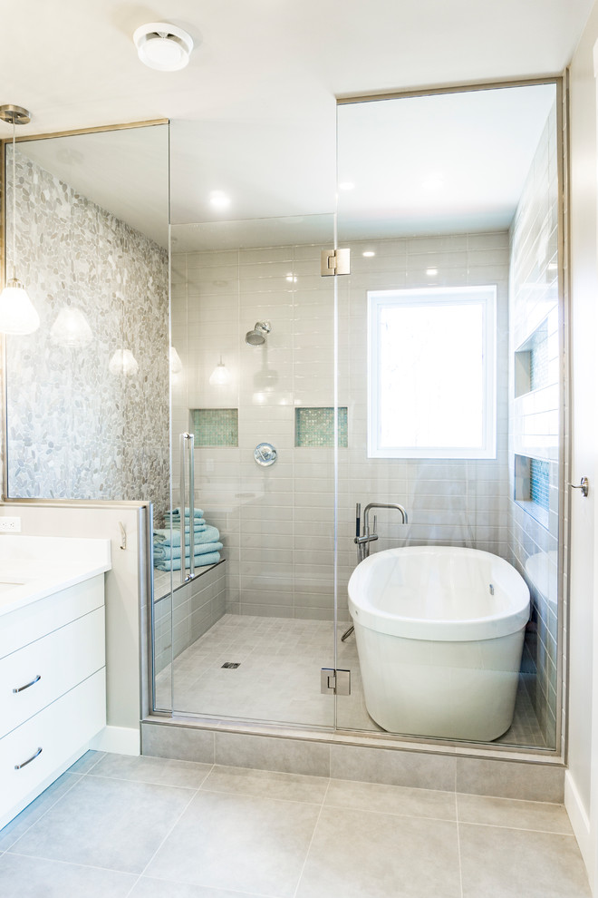 Large contemporary bathroom in Edmonton with flat-panel cabinets, white cabinets, a freestanding bath, a one-piece toilet, grey tiles, ceramic tiles, grey walls, ceramic flooring, a submerged sink, engineered stone worktops, grey floors and a hinged door.