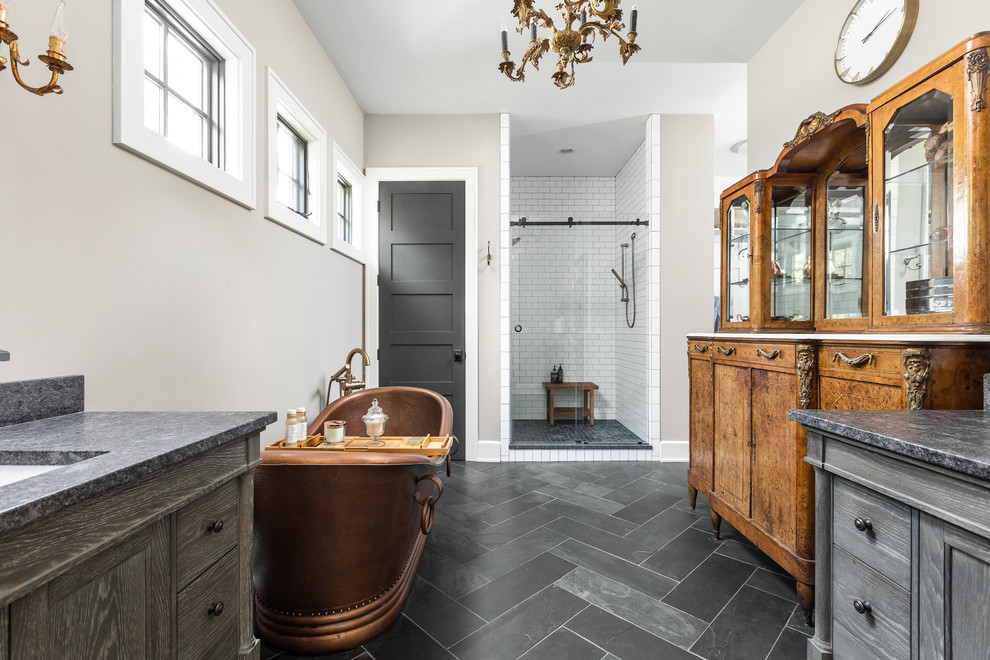 Inspiration pour une douche en alcôve principale rustique avec une baignoire indépendante, un sol gris, un plan de toilette noir, un mur gris et un placard avec porte à panneau encastré.
