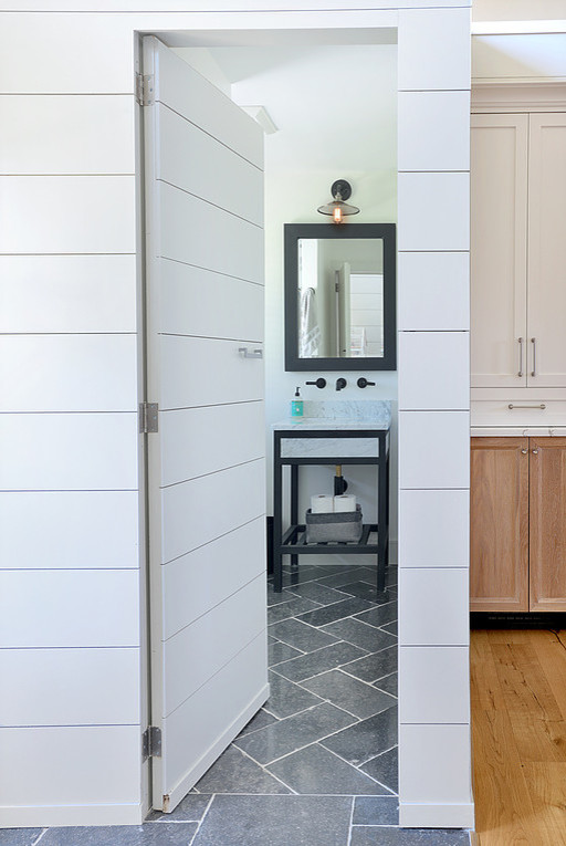 Photo of a medium sized country family bathroom in New York with a corner shower, a two-piece toilet, white walls, limestone flooring, a submerged sink, marble worktops, grey floors, a hinged door, white worktops, freestanding cabinets, black cabinets, white tiles and metro tiles.