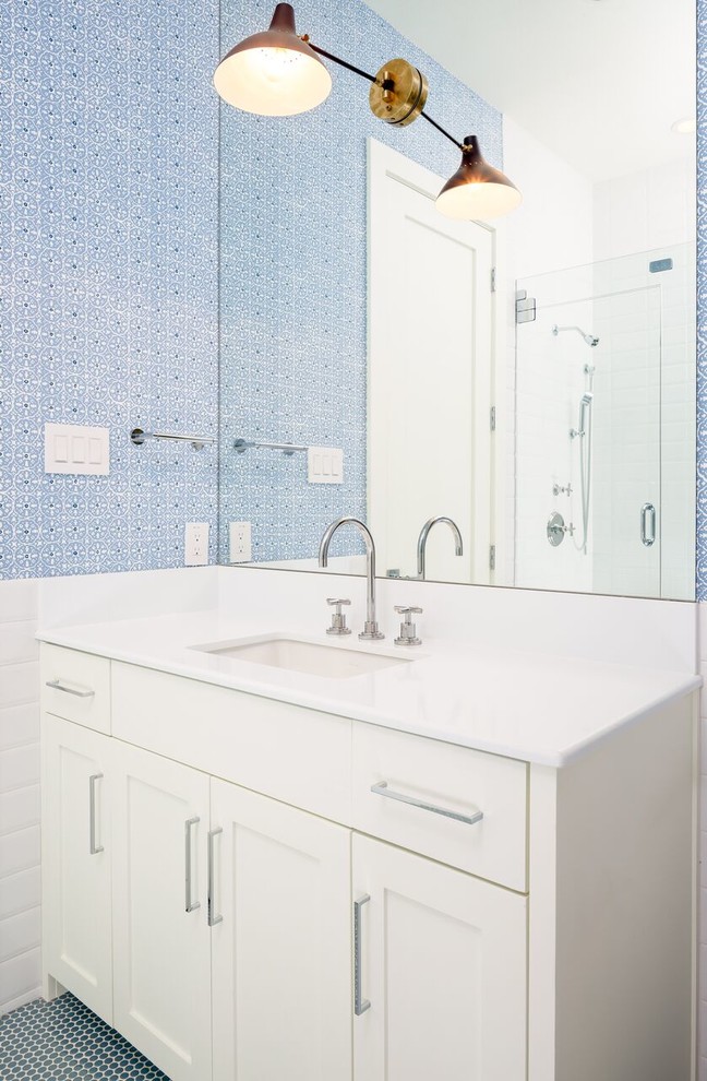 Modelo de cuarto de baño tradicional de tamaño medio con armarios estilo shaker, puertas de armario blancas, ducha esquinera, paredes azules, suelo con mosaicos de baldosas, aseo y ducha, lavabo bajoencimera y encimera de esteatita