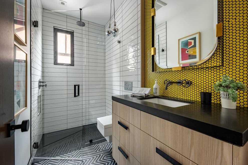 Réalisation d'une douche en alcôve grise et jaune design en bois clair avec un placard à porte plane, un carrelage jaune, mosaïque, un lavabo encastré, un sol noir et un plan de toilette noir.