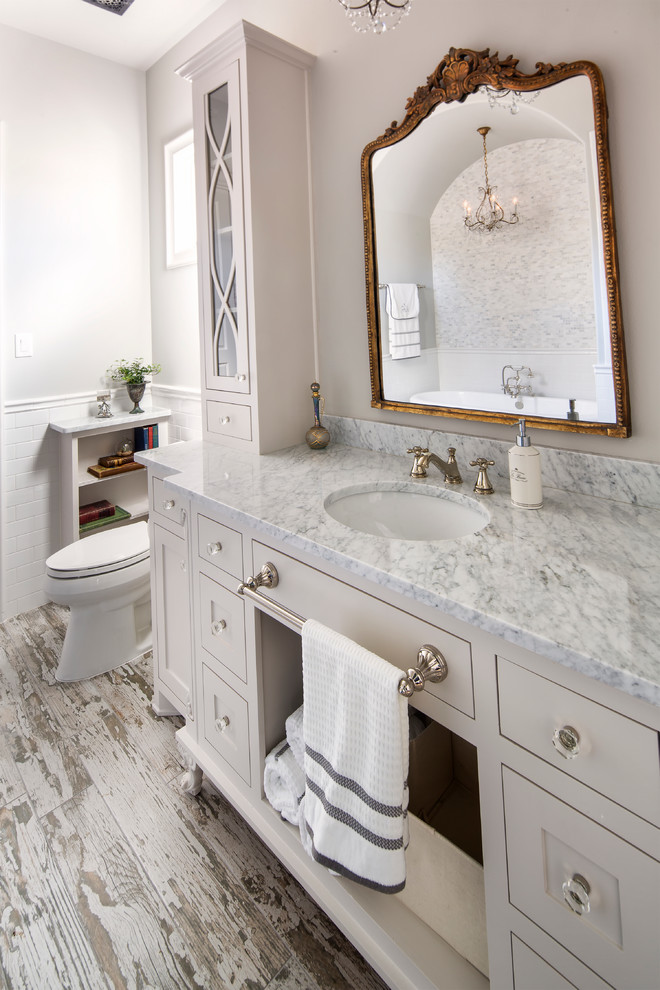 Design ideas for a medium sized country ensuite bathroom in Dallas with shaker cabinets, white cabinets, a freestanding bath, a two-piece toilet, white tiles, metro tiles, white walls, light hardwood flooring, a submerged sink and marble worktops.