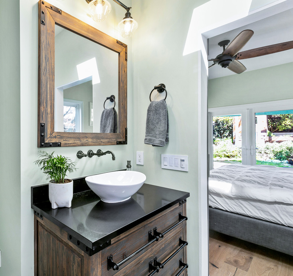 Photo of a medium sized farmhouse ensuite bathroom in Los Angeles with freestanding cabinets, medium wood cabinets, a freestanding bath, multi-coloured tiles, porcelain tiles, green walls, porcelain flooring, a vessel sink, beige floors and black worktops.