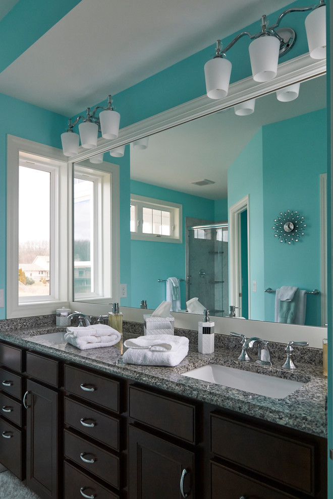 Exemple d'une salle de bain principale chic en bois foncé de taille moyenne avec un placard avec porte à panneau encastré, un mur bleu, un lavabo encastré, un plan de toilette en granite et un plan de toilette gris.