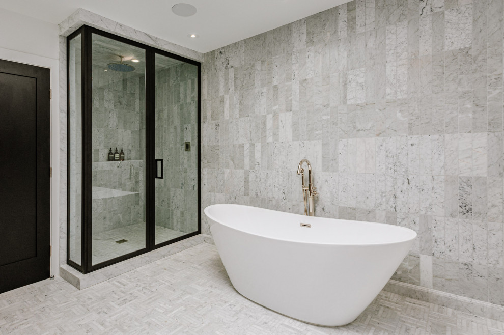 Cette photo montre une salle de bain principale nature de taille moyenne avec une baignoire indépendante, un espace douche bain, un carrelage gris, du carrelage en marbre, un mur blanc, un sol en marbre, un sol gris et une cabine de douche à porte battante.