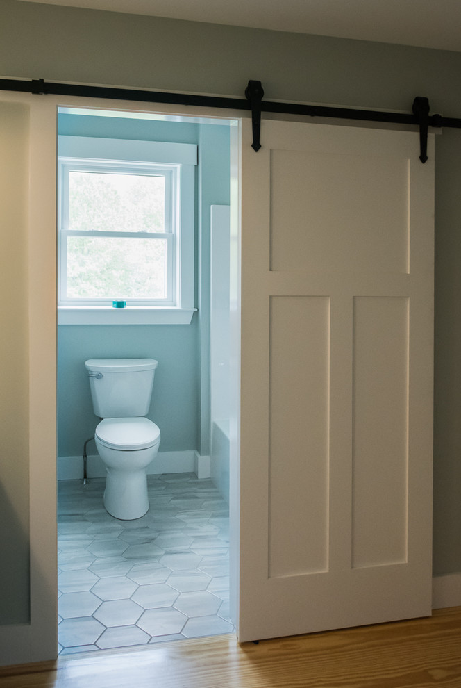 Aménagement d'une petite salle d'eau campagne avec un carrelage gris, un carrelage de pierre, un mur bleu, des portes de placard blanches, une baignoire en alcôve, un combiné douche/baignoire, WC séparés et un sol en carrelage de porcelaine.