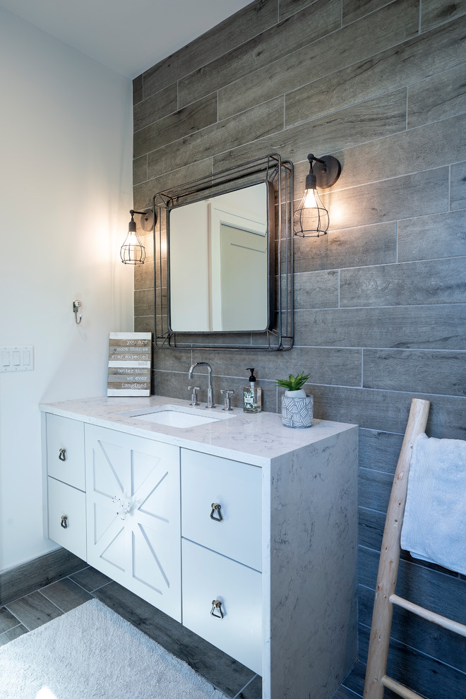 Bathroom - mid-sized country kids' gray tile and porcelain tile porcelain tile and gray floor bathroom idea in Atlanta with furniture-like cabinets, gray cabinets, a one-piece toilet, white walls, an undermount sink, quartz countertops and white countertops