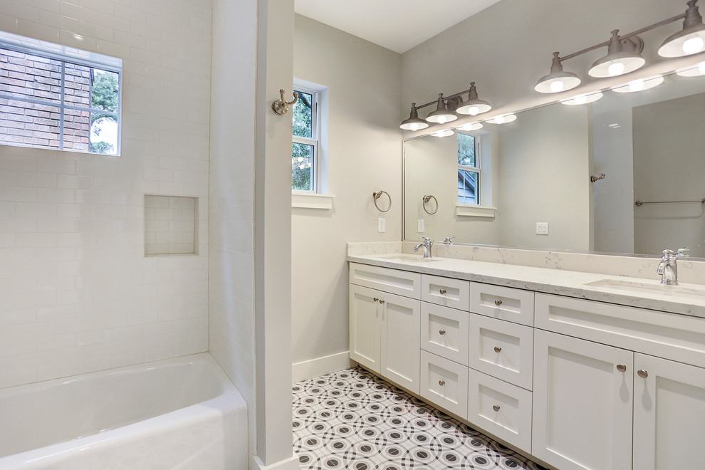 Пример оригинального дизайна: ванная комната среднего размера в стиле кантри с белыми фасадами, накладной ванной, душем над ванной, белой плиткой, керамической плиткой, серыми стенами, полом из мозаичной плитки, врезной раковиной, мраморной столешницей, фасадами в стиле шейкер, душевой кабиной и разноцветным полом