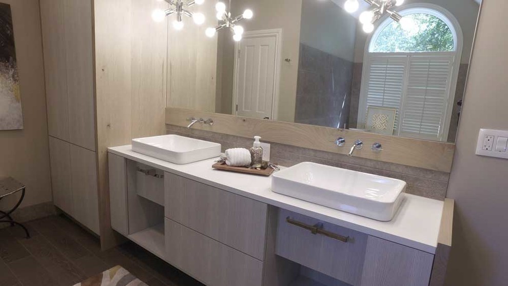Large modern ensuite bathroom in Wichita with flat-panel cabinets, grey cabinets, a corner bath, a corner shower, grey walls, a hinged door, beige tiles, porcelain tiles, a vessel sink and solid surface worktops.