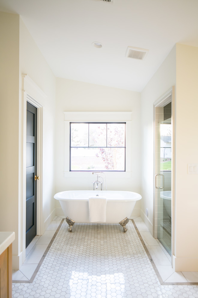 На фото: главная ванная комната среднего размера в стиле кантри с фасадами с утопленной филенкой, светлыми деревянными фасадами, ванной на ножках, белой плиткой, мраморным полом, столешницей из искусственного кварца, белым полом и душем с распашными дверями