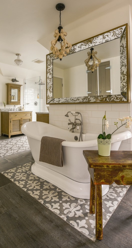 Cette image montre une salle de bain rustique en bois brun avec une baignoire indépendante, un carrelage blanc, un carrelage métro, un mur blanc, un sol gris, un plan de toilette blanc et un placard à porte persienne.