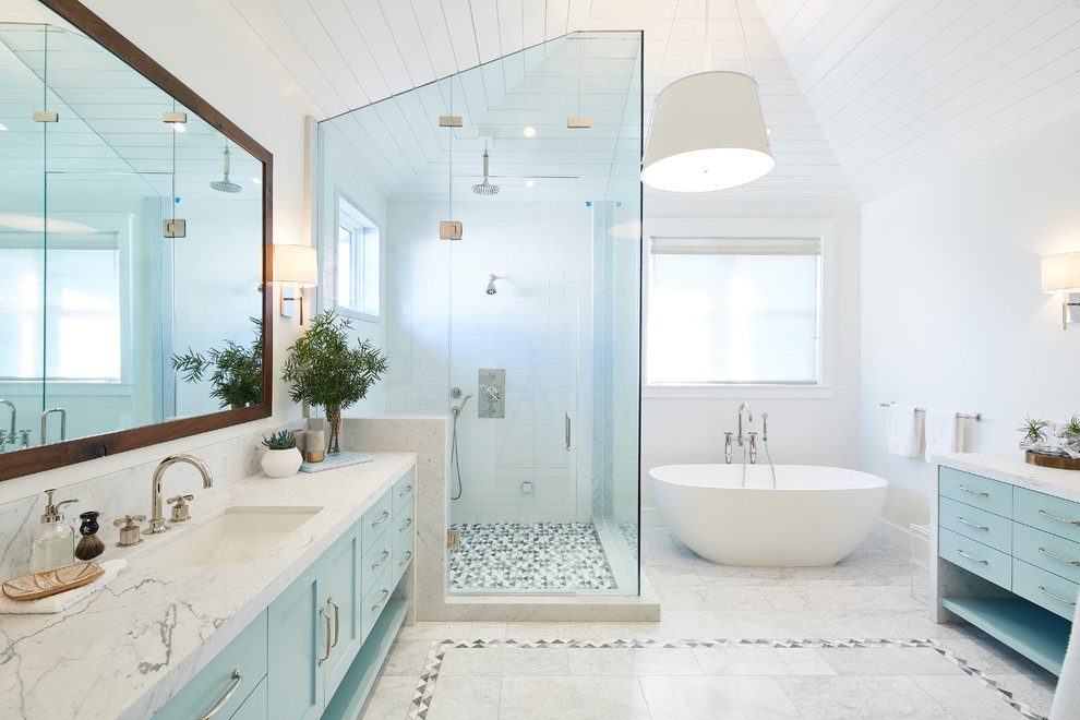Пример оригинального дизайна: ванная комната в морском стиле с фасадами в стиле шейкер, синими фасадами, отдельно стоящей ванной, угловым душем, белой плиткой, плиткой кабанчик, белыми стенами, врезной раковиной, белым полом, душем с распашными дверями и белой столешницей