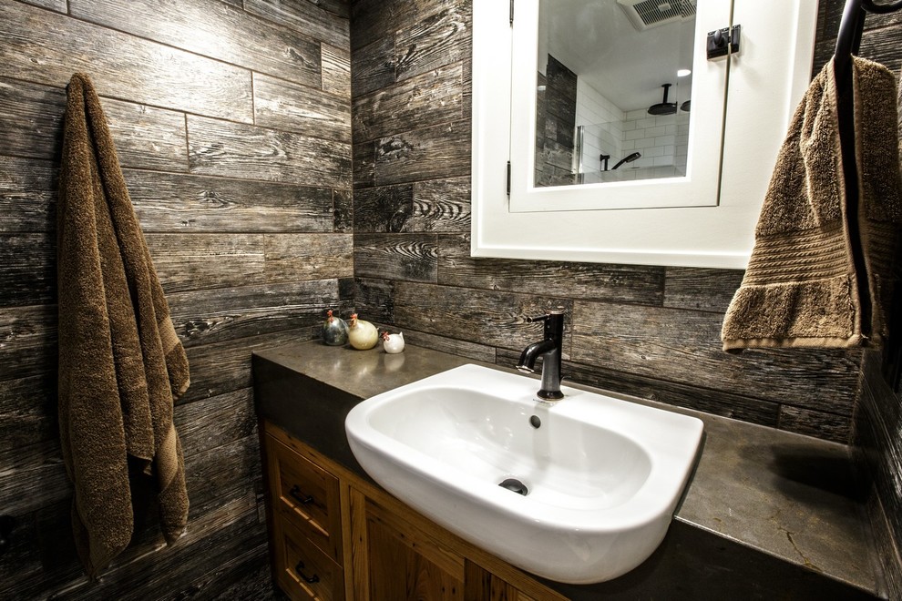 Bild på ett litet lantligt badrum, med ett nedsänkt handfat, skåp i shakerstil, skåp i mellenmörkt trä, bänkskiva i betong, en kantlös dusch, en vägghängd toalettstol, grå kakel, porslinskakel, grå väggar och klinkergolv i porslin