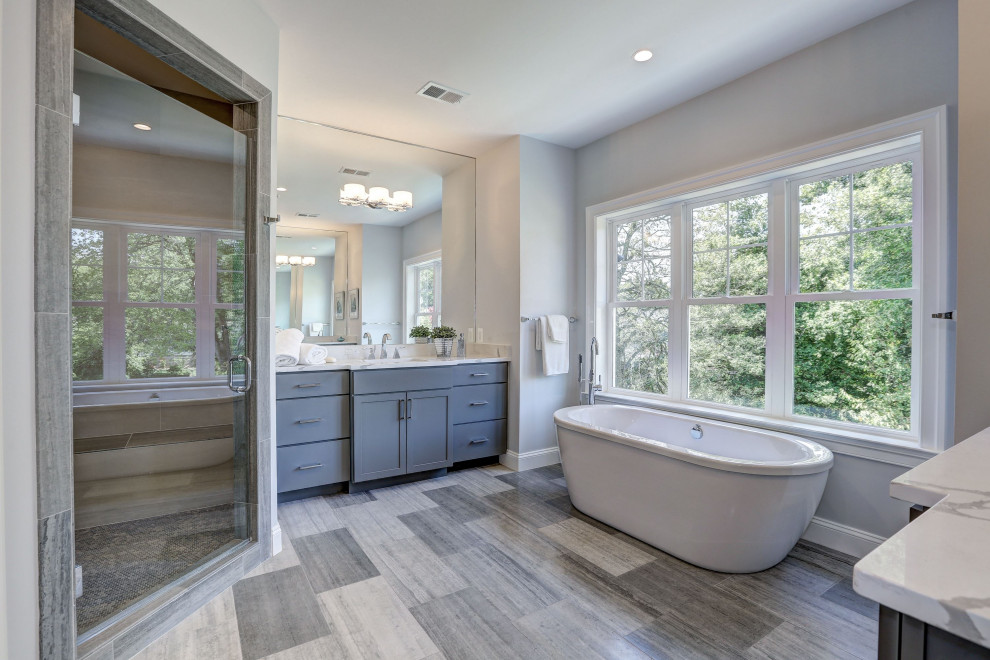This is an example of a large classic ensuite bathroom in DC Metro with recessed-panel cabinets, a freestanding bath, white worktops, grey cabinets, an alcove shower, grey walls, a submerged sink, grey floors and a hinged door.